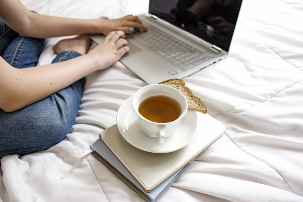 woman sitting on a bed with tea and a laptop making money online