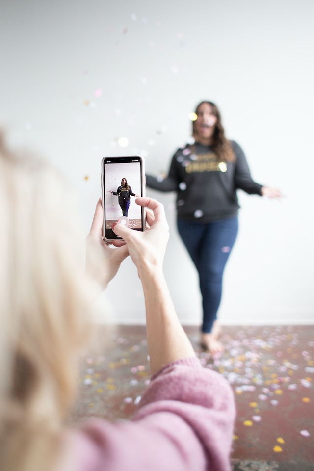 image of a woman taking a video of another woman throwing confetti