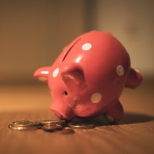 pink piggy bank tipped over spilling change on a table